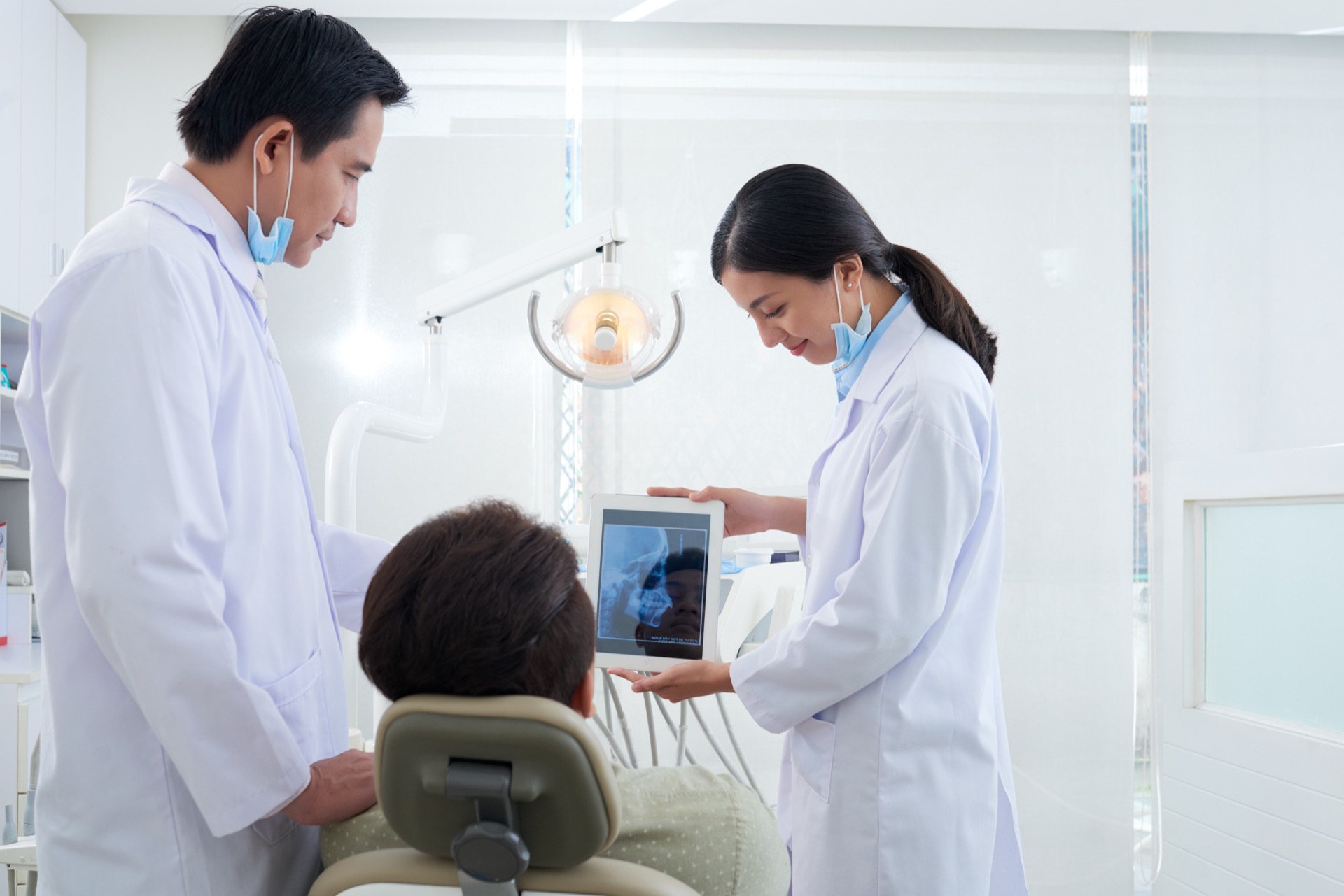 A smiling Malaysian patient seated comfortably in a bright dental chair